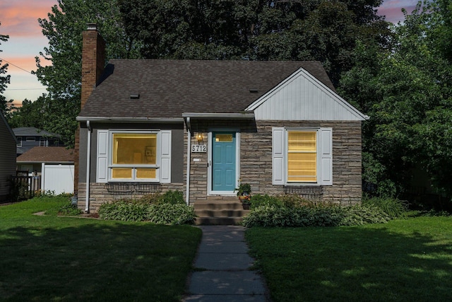 5712 Grand Ave S, Minneapolis, MN 55419 - view of front of property with stone siding, a chimney, a lawn, and roof with shingles