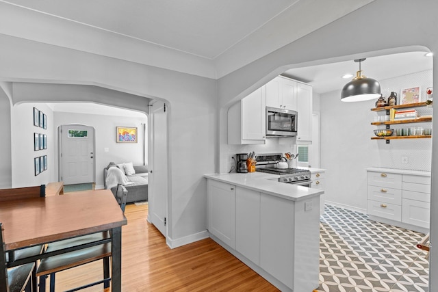 5712 Grand Ave S, Minneapolis, MN 55419 - kitchen featuring appliances with stainless steel finishes, arched walkways, light countertops, white cabinetry, and a peninsula