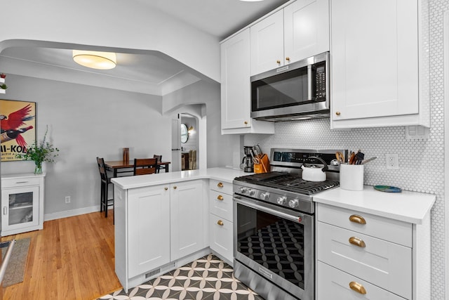 5712 Grand Ave S, Minneapolis, MN 55419 - kitchen featuring appliances with stainless steel finishes, a peninsula, light countertops, and white cabinets
