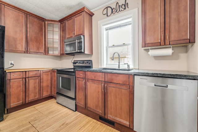 515 Lincoln St, Winona, MN 55987 - kitchen featuring appliances with stainless steel finishes, light wood-type flooring, glass insert cabinets, and brown cabinetry