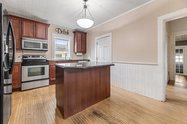515 Lincoln St, Winona, MN 55987 - kitchen with appliances with stainless steel finishes, dark countertops, a wainscoted wall, light wood-style flooring, and a center island