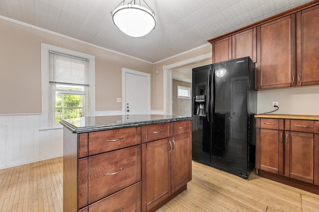 515 Lincoln St, Winona, MN 55987 - kitchen with black fridge, light wood-style flooring, a center island, a wainscoted wall, and ornamental molding