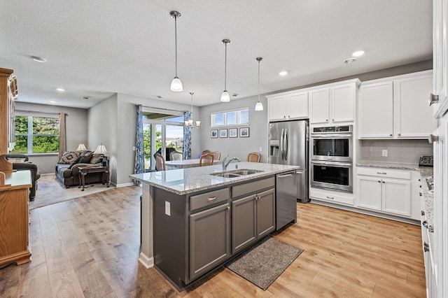 4870 Copper Ridge Dr, Woodbury, MN 55129 - kitchen featuring appliances with stainless steel finishes, gray cabinets, light wood finished floors, open floor plan, and recessed lighting