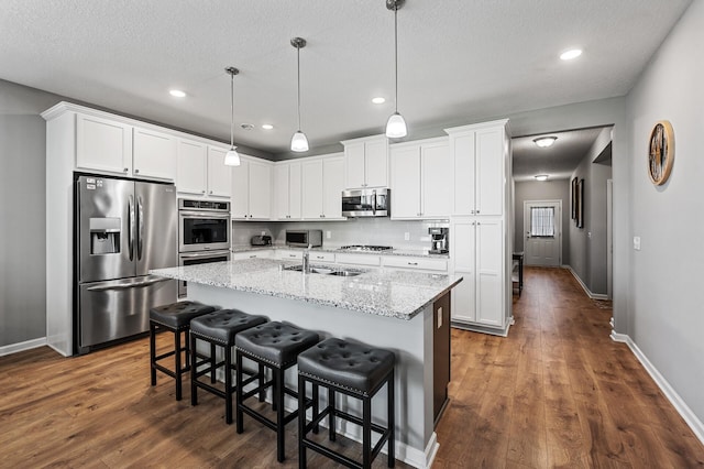 4870 Copper Ridge Dr, Woodbury, MN 55129 - kitchen featuring stainless steel appliances, dark wood-style floors, white cabinets, an island with sink, and recessed lighting