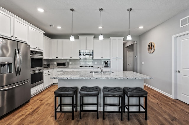 4870 Copper Ridge Dr, Woodbury, MN 55129 - kitchen with stainless steel appliances, white cabinets, a kitchen breakfast bar, and recessed lighting