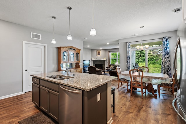 4870 Copper Ridge Dr, Woodbury, MN 55129 - kitchen featuring stainless steel appliances, a fireplace, dark wood finished floors, a textured ceiling, and decorative light fixtures