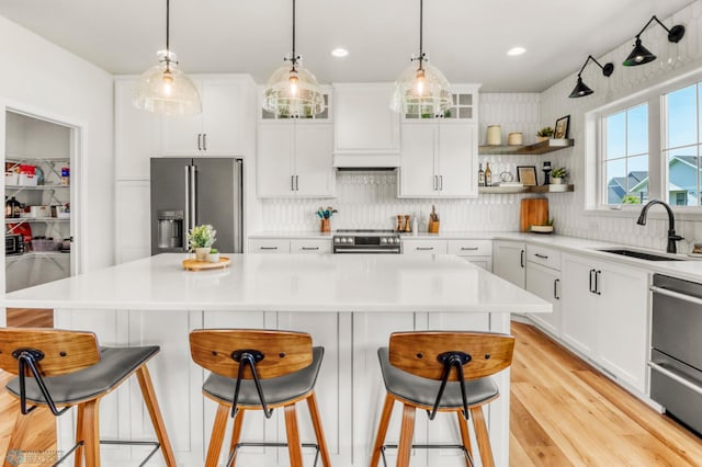 6176 Marigold Loop S, Fargo, ND 58104 - kitchen featuring appliances with stainless steel finishes, backsplash, glass insert cabinets, light wood-style flooring, and a breakfast bar area