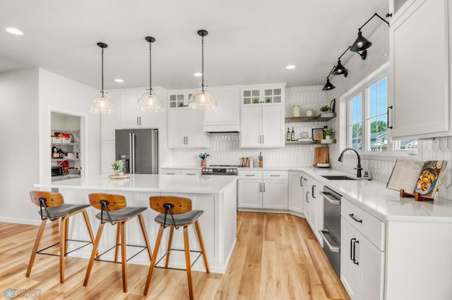 6176 Marigold Loop S, Fargo, ND 58104 - kitchen with appliances with stainless steel finishes, a center island, open shelves, light wood-style floors, and a kitchen breakfast bar