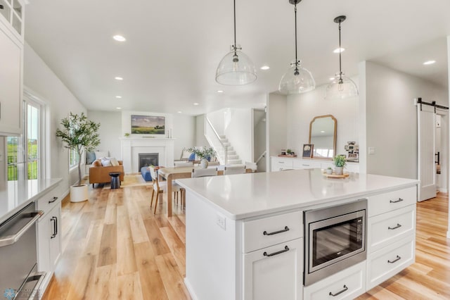 6176 Marigold Loop S, Fargo, ND 58104 - kitchen featuring stainless steel appliances, a barn door, a glass covered fireplace, recessed lighting, and light wood-style flooring