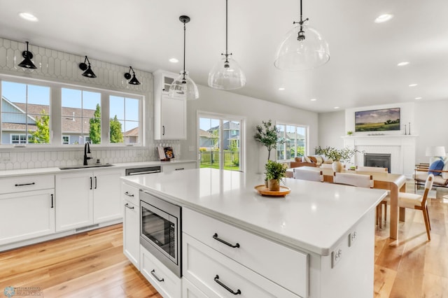 6176 Marigold Loop S, Fargo, ND 58104 - kitchen with stainless steel microwave, light wood-style flooring, recessed lighting, decorative backsplash, and light countertops