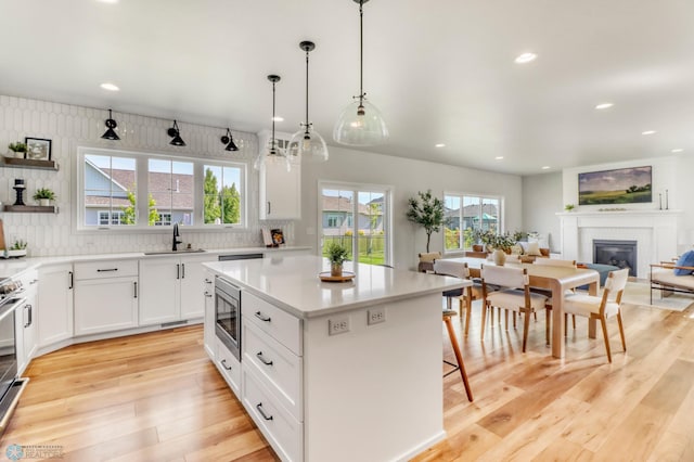 6176 Marigold Loop S, Fargo, ND 58104 - kitchen with appliances with stainless steel finishes, a glass covered fireplace, light wood-style floors, backsplash, and recessed lighting