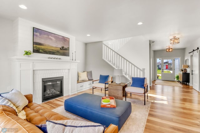 6176 Marigold Loop S, Fargo, ND 58104 - living room featuring light wood-type flooring, stairway, a barn door, recessed lighting, and a glass covered fireplace
