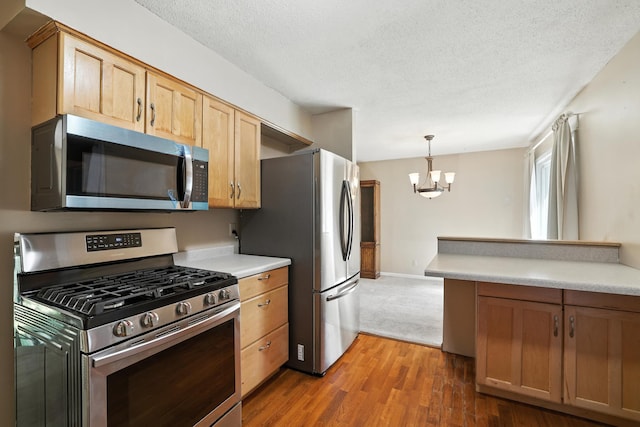1958 6th St N, North Saint Paul, MN 55109 - kitchen with appliances with stainless steel finishes, a chandelier, light countertops, wood finished floors, and a textured ceiling