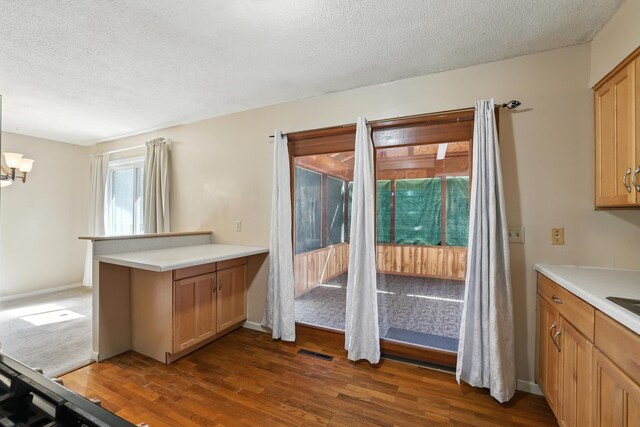 1958 6th St N, North Saint Paul, MN 55109 - kitchen with a textured ceiling, dark wood-style floors, light countertops, a peninsula, and a chandelier
