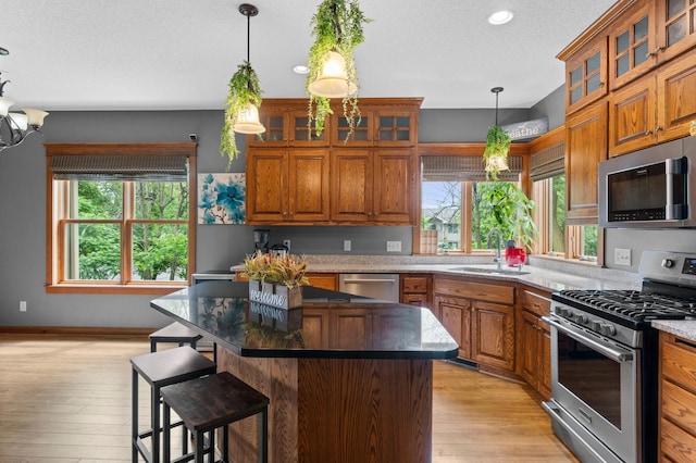 1222 81st Ct N, Brooklyn Park, MN 55444 - kitchen with stainless steel appliances, brown cabinets, a kitchen island, light wood-style flooring, and a textured ceiling