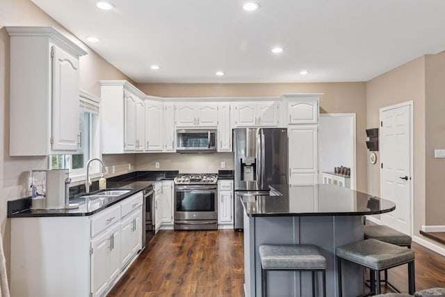 17964 Fresno St NW, Elk River, MN 55330 - kitchen featuring stainless steel appliances, dark countertops, a kitchen breakfast bar, white cabinetry, and recessed lighting