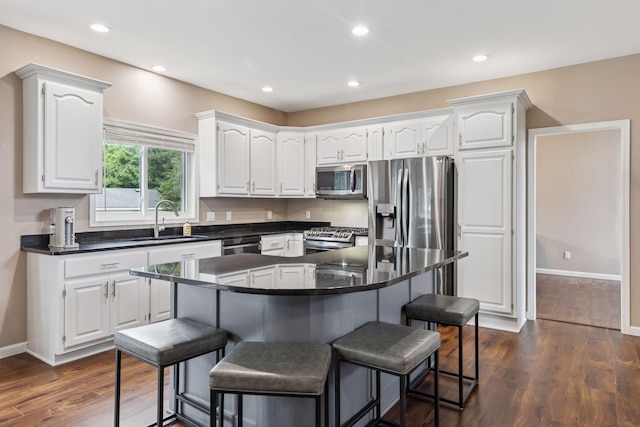 17964 Fresno St NW, Elk River, MN 55330 - kitchen with appliances with stainless steel finishes, dark countertops, a kitchen breakfast bar, white cabinetry, and recessed lighting
