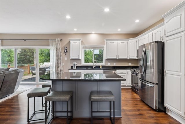 17964 Fresno St NW, Elk River, MN 55330 - kitchen featuring appliances with stainless steel finishes, a breakfast bar area, dark countertops, white cabinetry, and recessed lighting