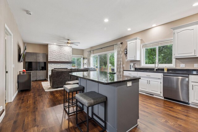 17964 Fresno St NW, Elk River, MN 55330 - kitchen with dishwasher, a kitchen bar, a ceiling fan, dark countertops, and white cabinets