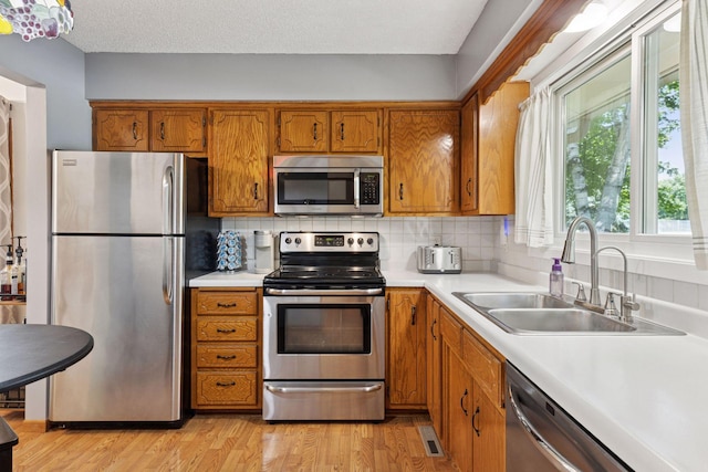 9743 Hemlock Ln N, Maple Grove, MN 55369 - kitchen featuring stainless steel appliances, brown cabinetry, and light countertops