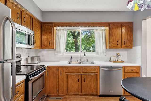 9743 Hemlock Ln N, Maple Grove, MN 55369 - kitchen featuring stainless steel appliances, brown cabinetry, decorative backsplash, and light countertops