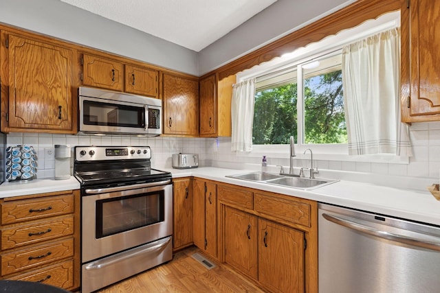 9743 Hemlock Ln N, Maple Grove, MN 55369 - kitchen with appliances with stainless steel finishes, brown cabinetry, light countertops, and backsplash