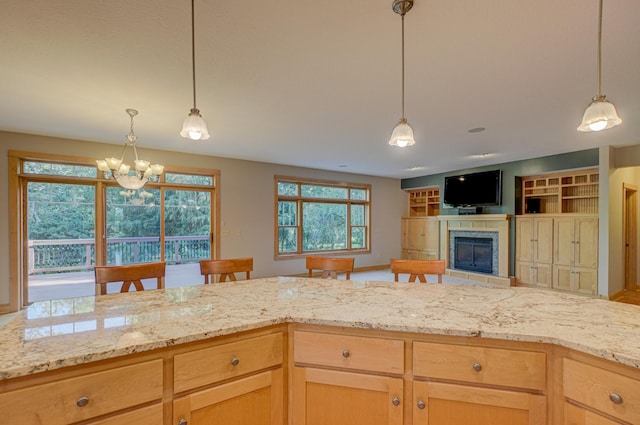442 Wren Ln, Hudson, WI 54016 - kitchen with light stone countertops, a fireplace, a chandelier, and pendant lighting