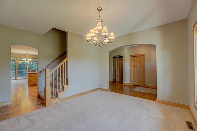 442 Wren Ln, Hudson, WI 54016 - carpeted spare room with a chandelier, arched walkways, wood finished floors, and stairs