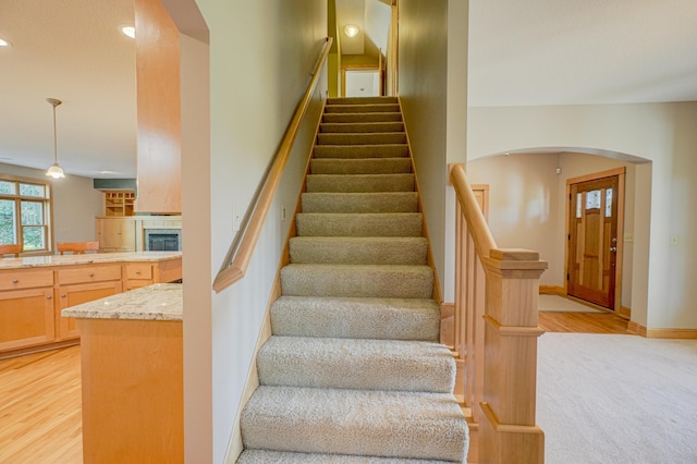442 Wren Ln, Hudson, WI 54016 - stairs featuring a tiled fireplace, arched walkways, recessed lighting, wood finished floors, and carpet floors