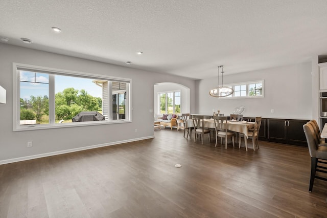 19400 75th Ave, Corcoran, MN 55340 - dining space featuring arched walkways, dark wood-type flooring, a chandelier, a textured ceiling, and recessed lighting