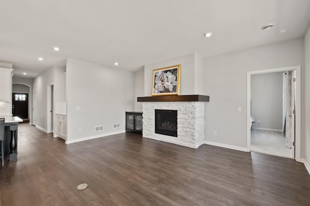 19400 75th Ave, Corcoran, MN 55340 - unfurnished living room featuring a stone fireplace, dark wood finished floors, recessed lighting, and arched walkways
