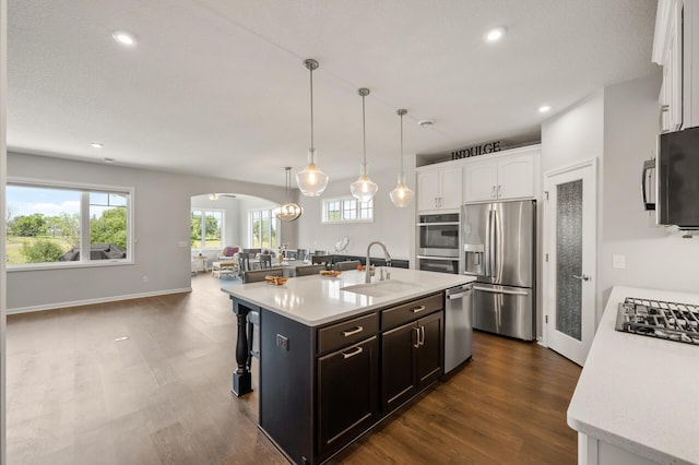 19400 75th Ave, Corcoran, MN 55340 - kitchen with appliances with stainless steel finishes, arched walkways, light countertops, open floor plan, and white cabinetry