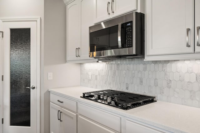 19400 75th Ave, Corcoran, MN 55340 - kitchen featuring stainless steel microwave, black gas stovetop, light countertops, backsplash, and white cabinets