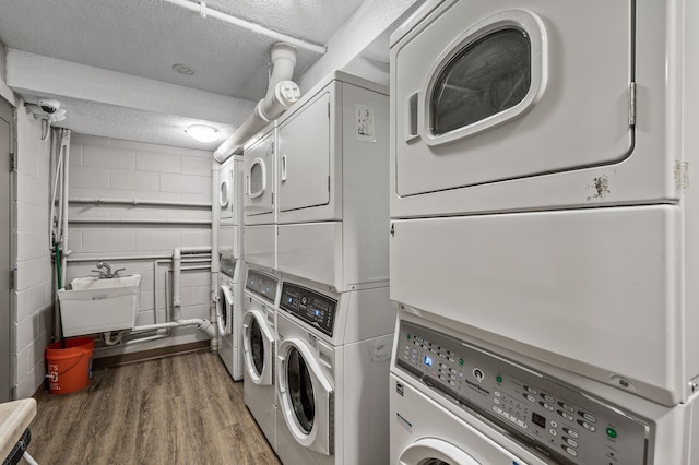 3729 Snelling Ave Unit 108, Minneapolis, MN 55406 - communal laundry room featuring stacked washer / dryer, independent washer and dryer, wood finished floors, a textured ceiling, and concrete block wall