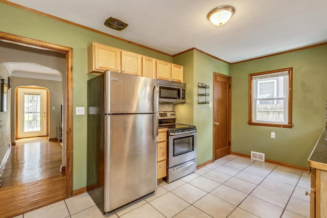 1821 Orange Ave E, Saint Paul, MN 55119 - kitchen featuring appliances with stainless steel finishes, light brown cabinetry, crown molding, arched walkways, and light tile patterned floors