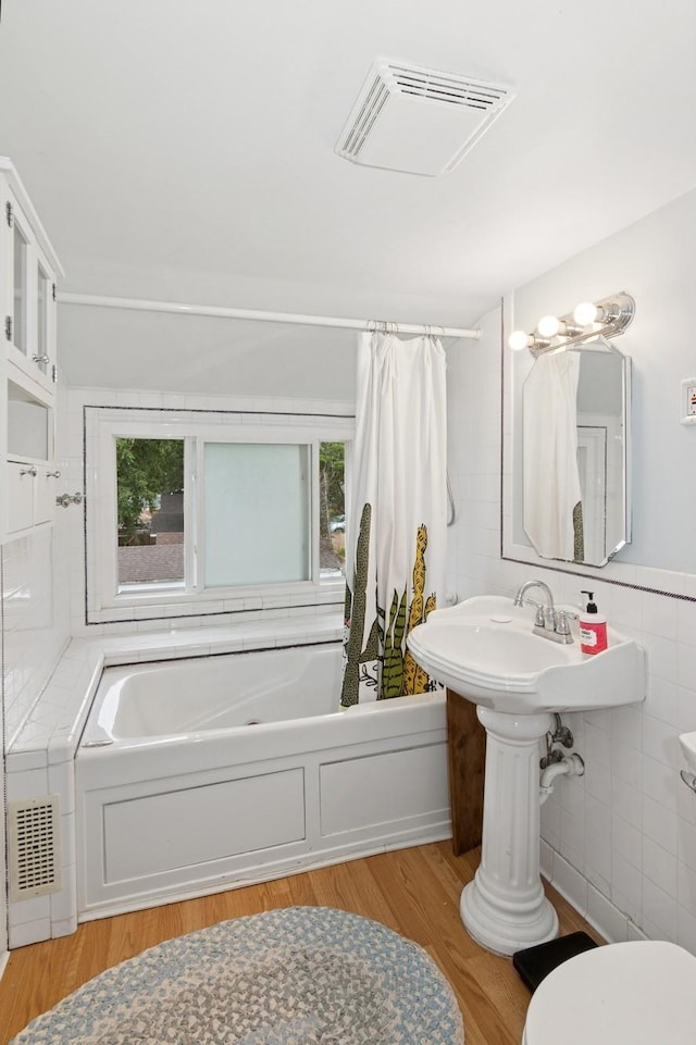 116 9th Ave NW, Rochester, MN 55901 - bathroom with tile walls, wood finished floors, and shower / bath combo with shower curtain