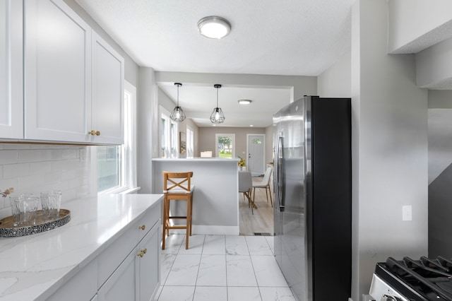 1634 Upton Ave N, Minneapolis, MN 55411 - kitchen with freestanding refrigerator, light marble finish flooring, hanging light fixtures, white cabinetry, and light stone countertops