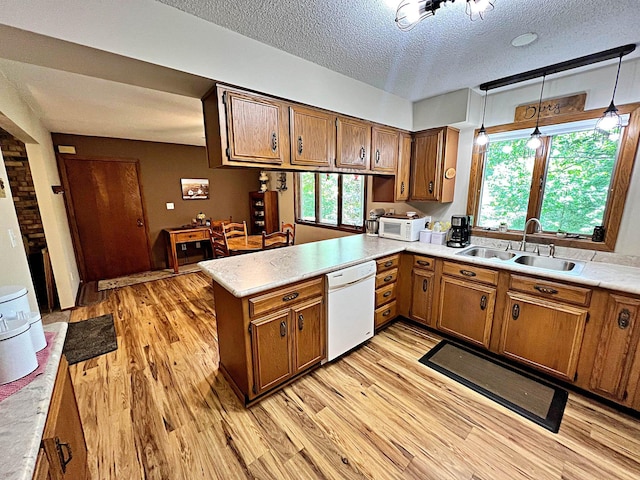 39631 342nd Ln, Aitkin, MN 56431 - kitchen featuring white appliances, a peninsula, brown cabinetry, light wood-style flooring, and a textured ceiling