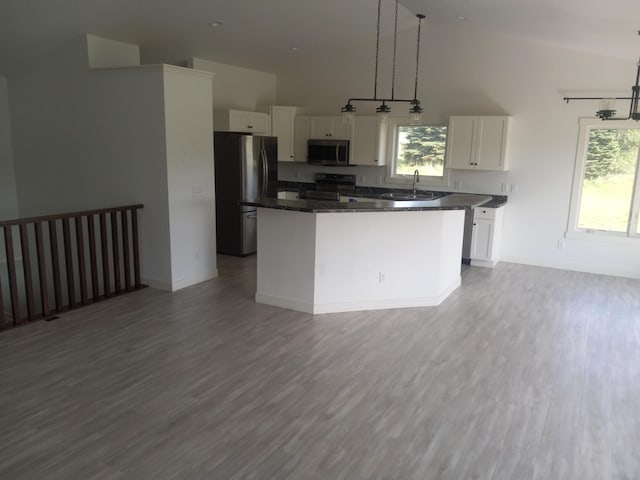 1267 146th Ave, New Richmond, WI 54017 - kitchen with stainless steel appliances, white cabinets, dark countertops, a kitchen island, and wood finished floors