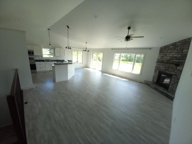 1267 146th Ave, New Richmond, WI 54017 - unfurnished living room with lofted ceiling, ceiling fan, a stone fireplace, and wood finished floors