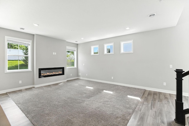 6450 Inspire Cir S, Cottage Grove, MN 55016 - unfurnished living room with plenty of natural light, a glass covered fireplace, wood finished floors, and recessed lighting