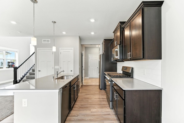 6450 Inspire Cir S, Cottage Grove, MN 55016 - kitchen with appliances with stainless steel finishes, light wood finished floors, dark brown cabinetry, a kitchen island with sink, and decorative backsplash