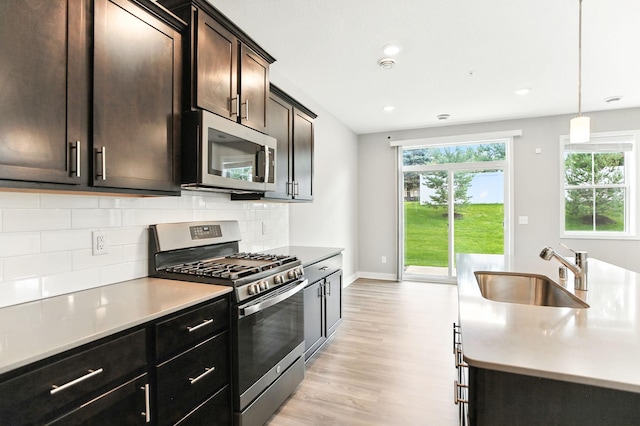 6450 Inspire Cir S, Cottage Grove, MN 55016 - kitchen with stainless steel appliances, light wood finished floors, backsplash, light countertops, and decorative light fixtures