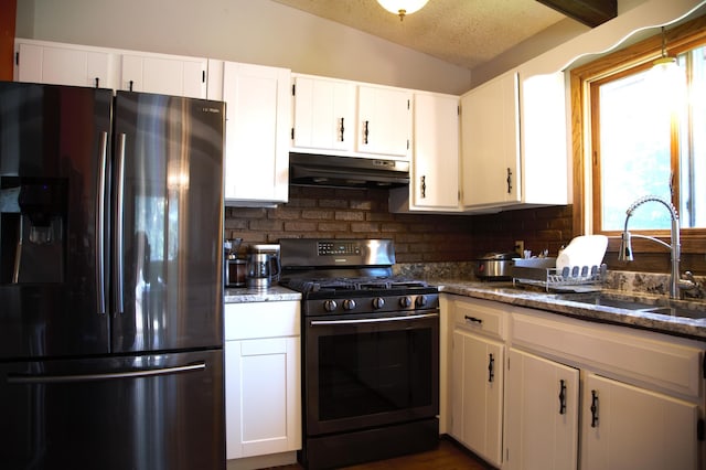 8301 Sumter Ave N, Brooklyn Park, MN 55445 - kitchen with refrigerator with ice dispenser, black gas range, under cabinet range hood, tasteful backsplash, and white cabinets