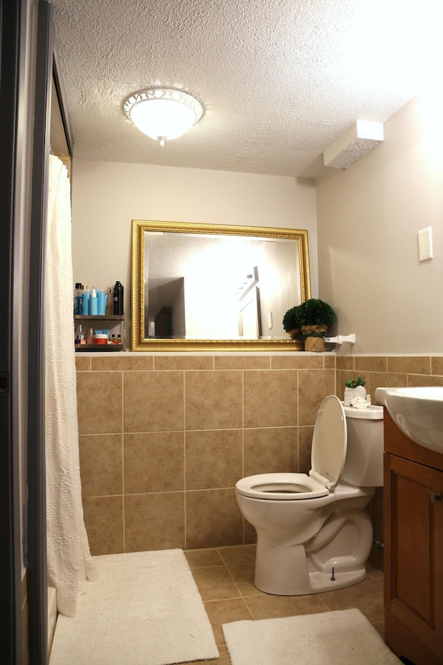 8301 Sumter Ave N, Brooklyn Park, MN 55445 - bathroom with tile walls, vanity, curtained shower, a wainscoted wall, and tile patterned flooring