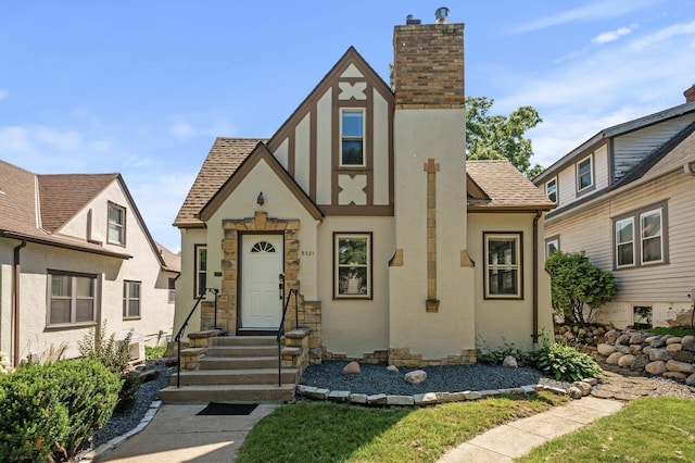 5321 Park Ave, Minneapolis, MN 55417 - tudor-style house with stucco siding, roof with shingles, a chimney, and entry steps