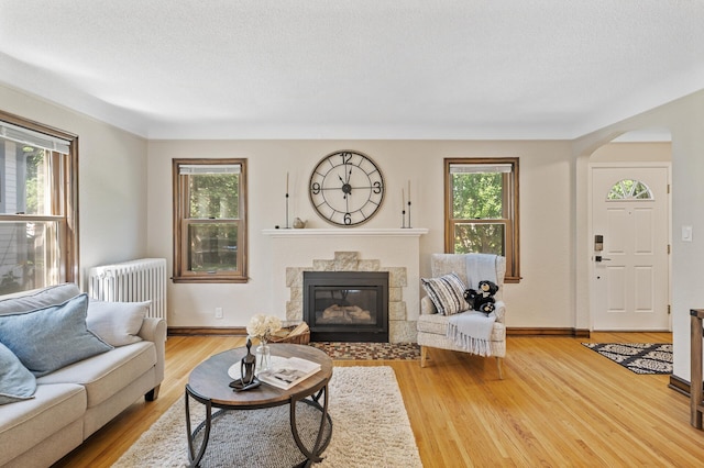 5321 Park Ave, Minneapolis, MN 55417 - living room featuring radiator heating unit, a fireplace, wood finished floors, and arched walkways