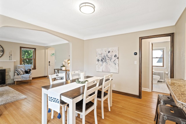 5321 Park Ave, Minneapolis, MN 55417 - dining area with arched walkways, light wood-type flooring, radiator heating unit, and a fireplace