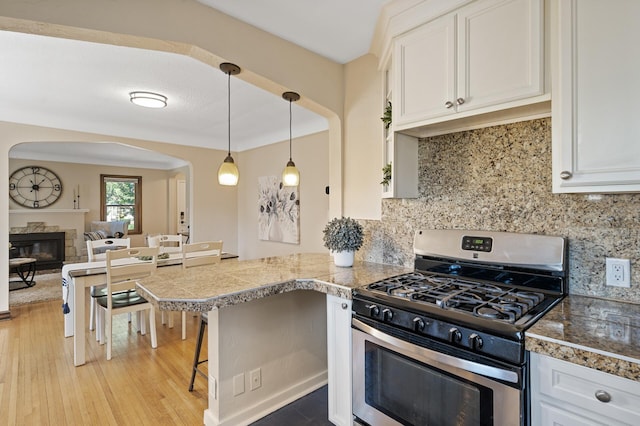 5321 Park Ave, Minneapolis, MN 55417 - kitchen featuring stainless steel range with gas stovetop, tile counters, arched walkways, and white cabinetry