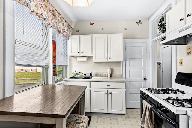 702 11th St, Duluth, MN 55805 - kitchen featuring white gas range oven, extractor fan, light flooring, and white cabinets